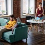 Pessoas em apartamento pequeno sentadas em sofá e mesa de café em uma sala de estar, criando um ambiente integrado amigável e confortável para conversas e convivência.