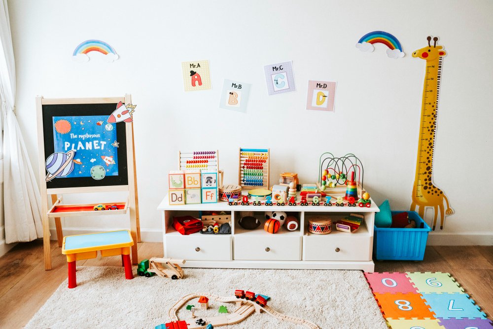 Espaço lúdico em quarto infantil com brinquedos variados e arco-íris alegres nas paredes do ambiente.